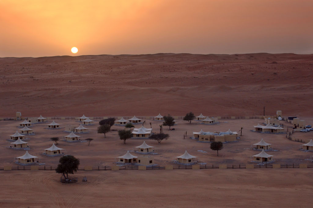 In the evening, the light of sunset shines on the earth and the pure white tents, setting a serene and mysterious mood
